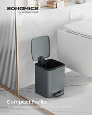 Slate grey pedal bin with the lid open standing beside a toilet on a marble bathroom floor