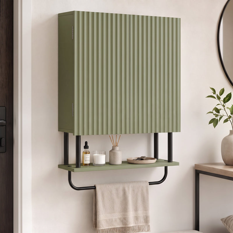 Green wall cabinet in a hallway with a reed diffuser on the open shelf and a towel on the rail