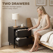 Black bedside cabinet with both drawers open showing storage space beside a bed