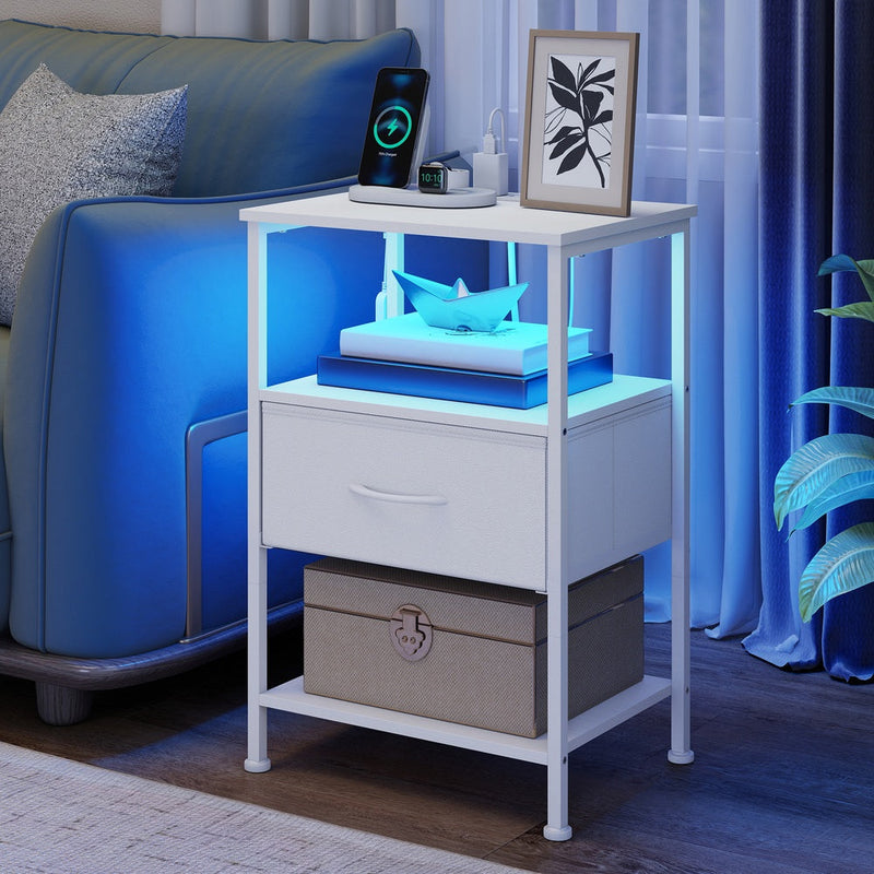 White bedside table in a living room with the shelf lit blue, a storage box on the lower shelf and a charging phone