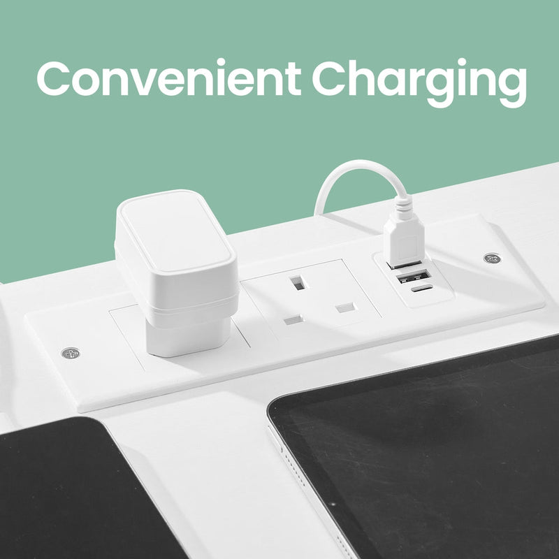 Close-up of the white charging panel set into the tabletop, showing two AC sockets alongside USB-A and USB-C ports