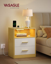 Bedside table next to a bed with a table lamp and phone charging