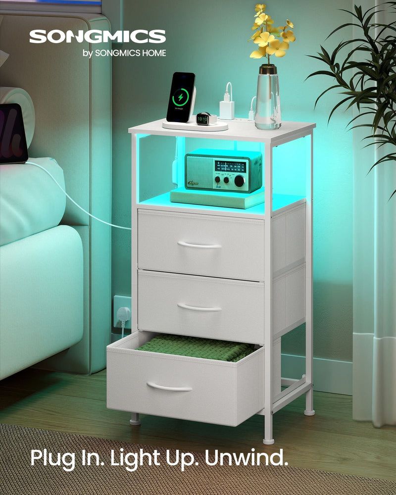 Cloud White bedside table styled beside a bed with turquoise LED light glowing under the open shelf and a phone charging on top