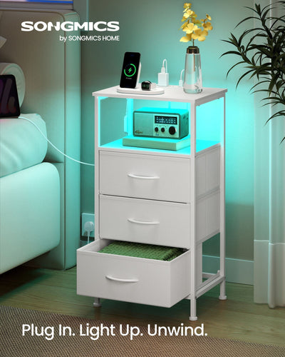 Cloud White bedside table styled beside a bed with turquoise LED light glowing under the open shelf and a phone charging on top
