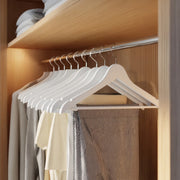Birch wood coat hanger holding a strappy top on the shoulder notches