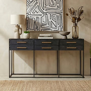 Console table styled in a living room with lamps and artwork above the black drawer front