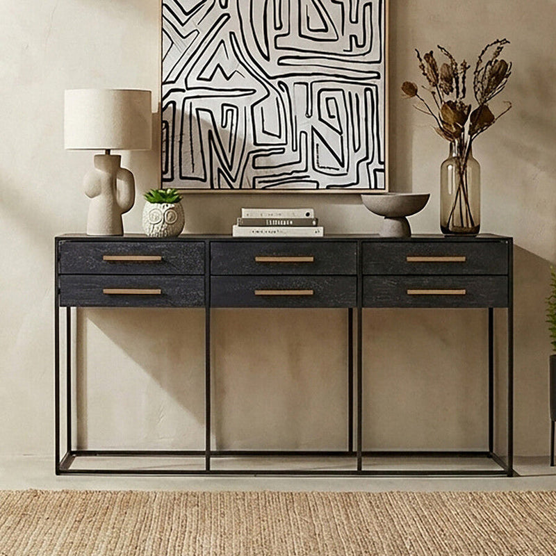 Console table styled in a living room with lamps and artwork above the black drawer front
