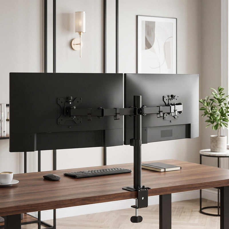 Two monitors on the stand above a keyboard in a bright home office