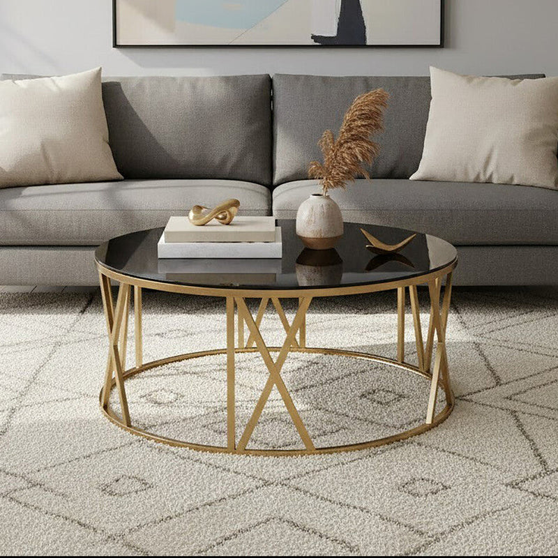 Black glass round coffee table with brushed gold frame styled in a modern living room