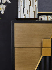 Black and gold side table styled beside a sofa in a contemporary living room