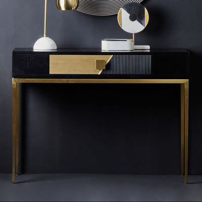 Black and gold fluted console table with gold handle styled in a hallway
