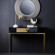 Black and gold console table styled behind a sofa in an open-plan living room