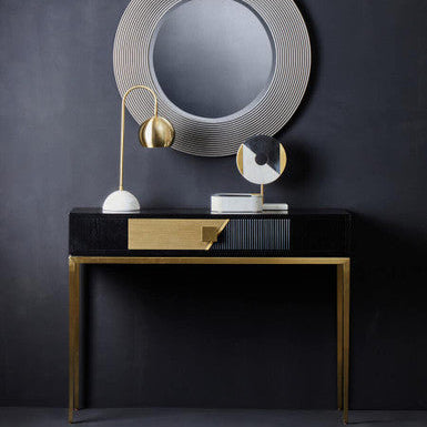 Black and gold console table styled behind a sofa in an open-plan living room