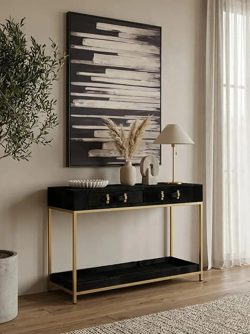 Console table styled in a living room with a lamp and art books on the top surface