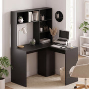 Black L-shaped corner desk in a home office corner with laptop and plants