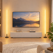 Two lit floor lamps either side of a TV unit in a living room