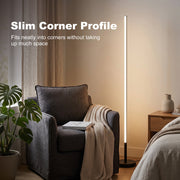Slim floor lamp in a bedroom corner beside an armchair and bedside table