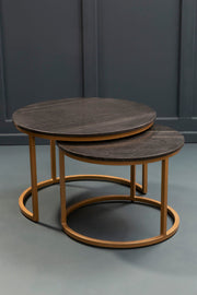 Nesting marble coffee tables in a living room setting with the smaller table pulled out beside an armchair