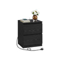 Black 2-drawer nightstand with a plugged-in charging station, books and a vase on top, on a plain background