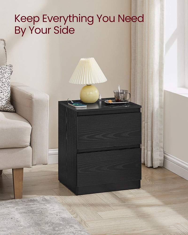 Black nightstand used as a living room side table with a table lamp, mug and armchair alongside