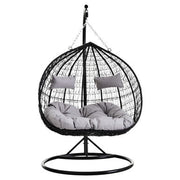 Black rattan double hanging chair with grey cushions, studio shot
