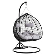 Black rattan double hanging chair with grey cushions, plain background