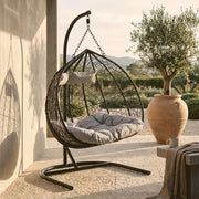 Black rattan double hanging chair with sledge base in an outdoor patio setting