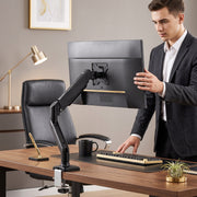 Man adjusting a monitor on the single arm at an office desk