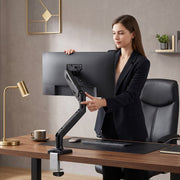 Woman moving a monitor on the single arm at her desk