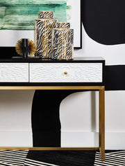 Black and gold console table styled behind a sofa in a contemporary living room