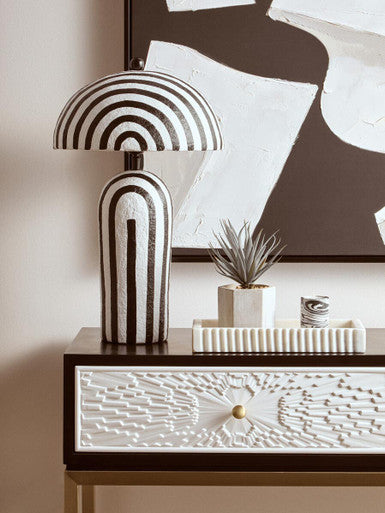 Console table styled in an entryway beneath a wall mirror with a vase and lamp