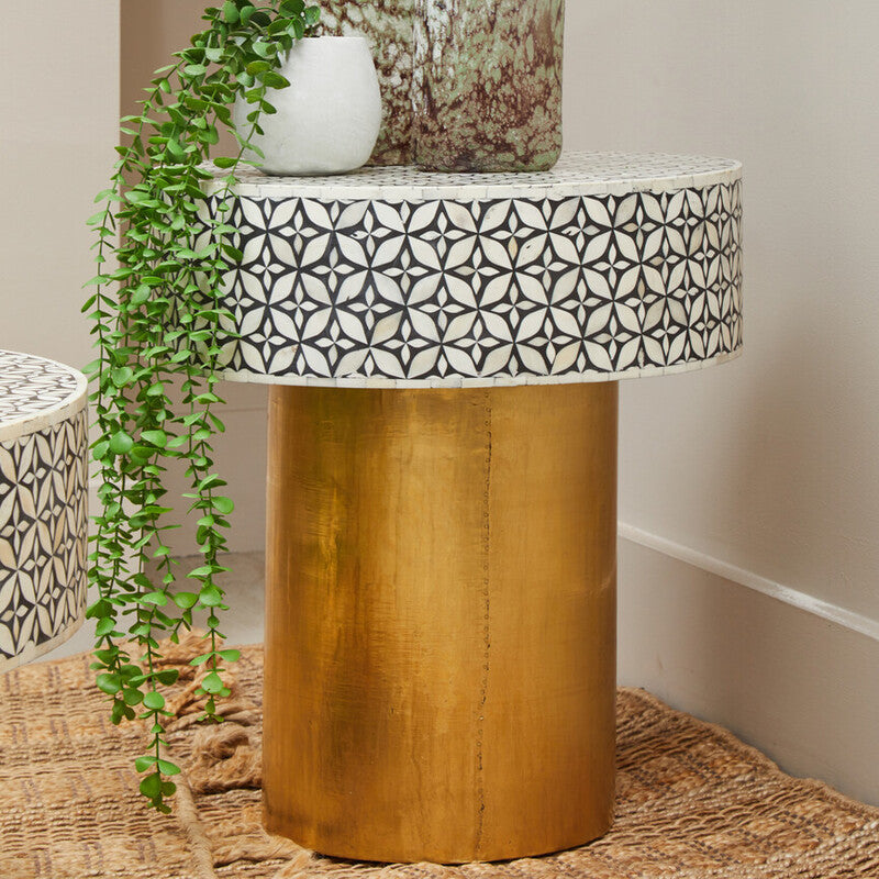 Black and white bone inlay round side table with gold column base beside a sofa