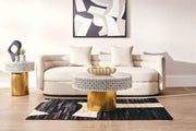 Gold column base of the round side table against a light living room floor