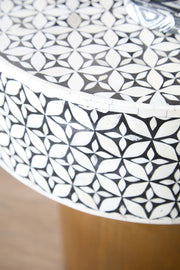 Bone inlay round side table in a styled interior beside an armchair