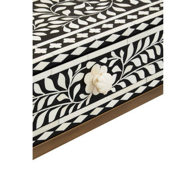 Macro close-up of the hand-laid white bone floral inlay on the black surface