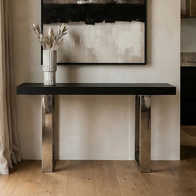Black wood and glass top console table with silver crossed legs styled in a hallway setting