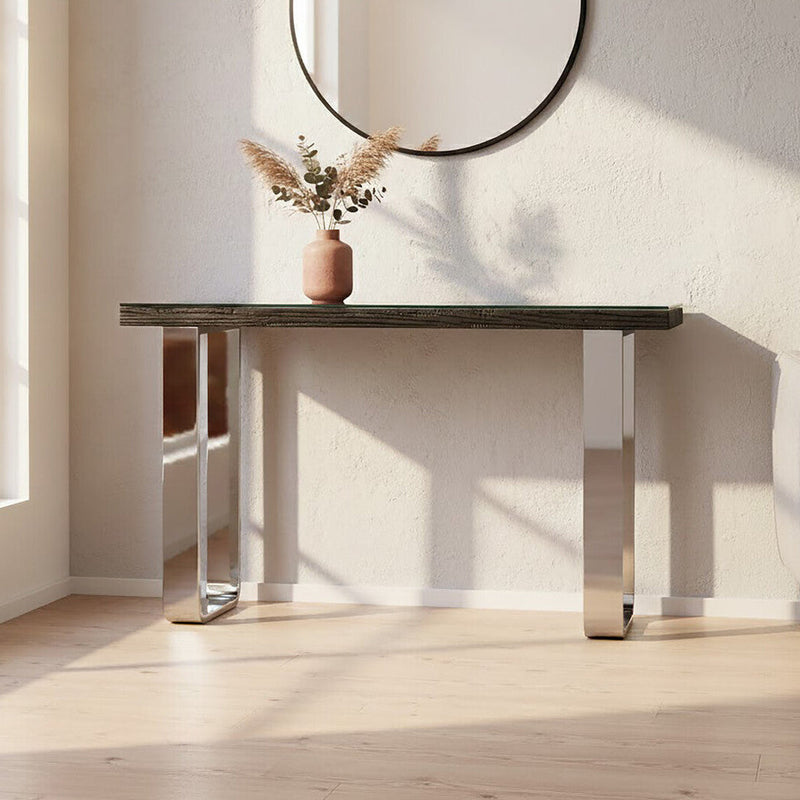 Black wood and clear glass console table with silver U-shaped legs styled in a modern hallway