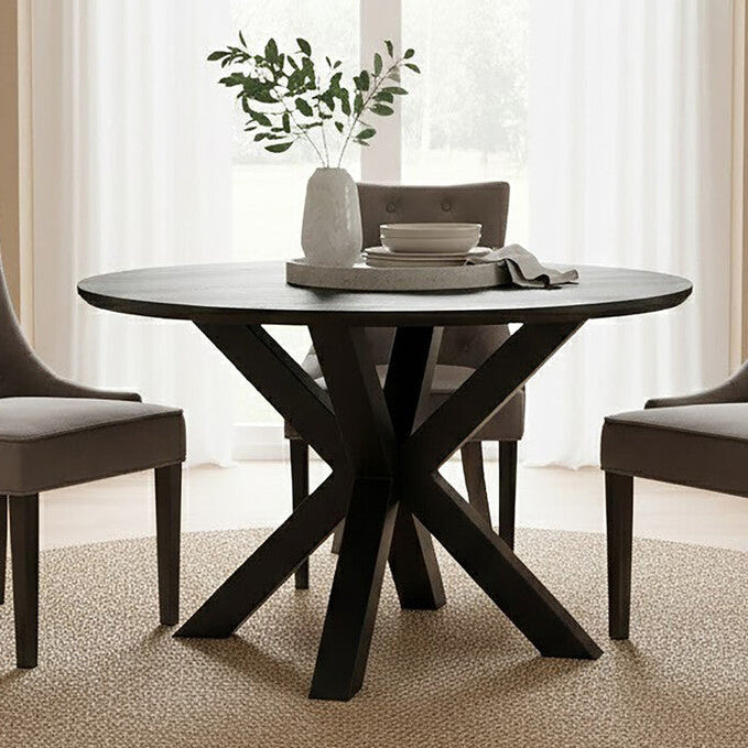 Black wood veneer round dining table styled in a dining room with upholstered chairs