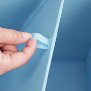 Close-up of a hand folding the inner panel of the blue fabric cube flat
