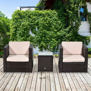 Brown rattan bistro set with two armchairs and side table on wooden decking in front of greenery