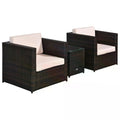 Two brown rattan armchairs with cream cushions and a glass-top side table on a white background