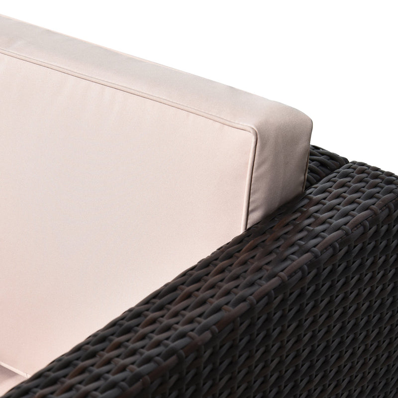 Close-up of the cream back cushion resting above the rattan armrest