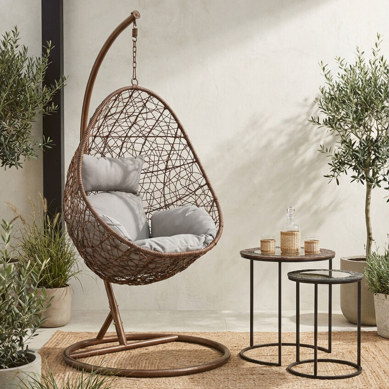 Brown rattan hanging chair shown in an outdoor patio setting