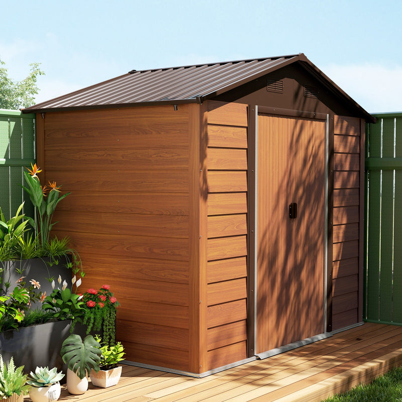 Wood effect shed on decking beside a green fence, surrounded by leafy potted plants