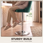 Person resting their feet on the chrome T-bar footrest of a dark green bar stool