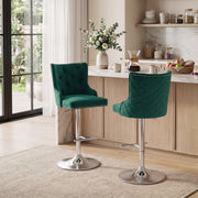 Two dark green button-tufted bar stools beside a light wood kitchen counter