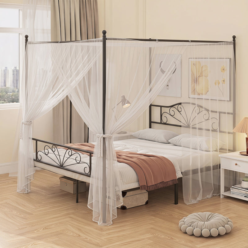 Black bed frame with a sheer mosquito net draped over the posts