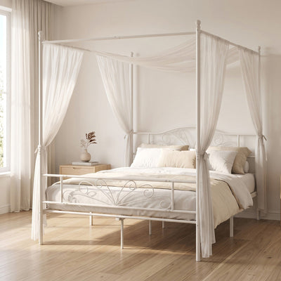 White canopy bed frame styled in a bedroom with sheer curtains