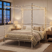 White canopy bed frame styled in a warm evening bedroom with fairy lights