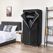 Black canvas wardrobe standing beside a double bed and a ladder bookshelf in a bedroom